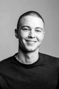 Black and white portrait of an adult man smiling, shot in Berlin.